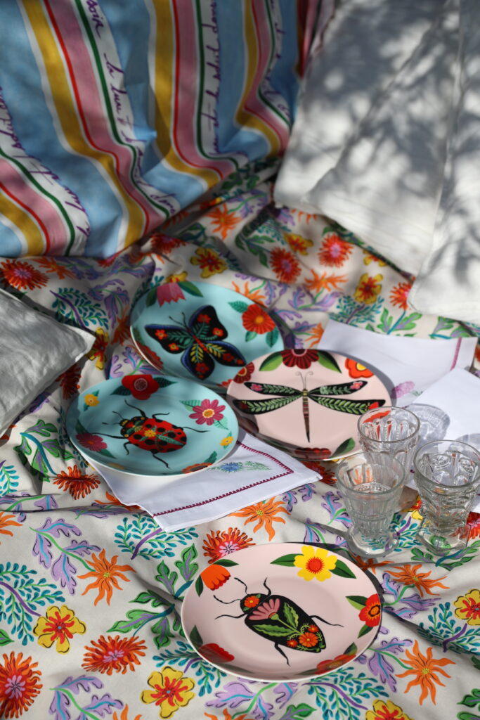 Plus que jamais, Fragonard revendique une inspiration vagabonde, nourrie par les terres chères à son histoire. Provence et Riviera dialoguent avec des influences lointaines dans un jeu de couleurs, de motifs et de matières pensé comme une invitation à l’évasion. Baptisée "L’Art du Mélange", cette nouvelle proposition célèbre un art de vivre joyeux et sensoriel, où les traditions locales se réinventent au contact d’imaginaires venus d’ailleurs. La collection se décline autour de pièces dédiées à la table et à la maison : nappes imprimées, serviettes brodées, torchons décoratifs, plateaux en bois, vaisselle en porcelaine et sets de table composent un univers riche et expressif. Motifs floraux, rayures poétiques et illustrations végétales s’y répondent dans une harmonie volontairement décomplexée.